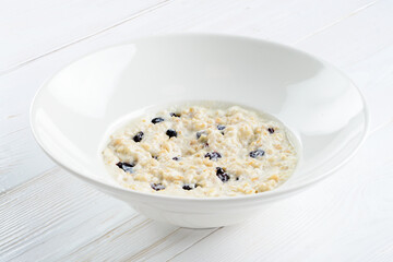 Vegetarian breakfast. Delicious oatmeal porridge with raisin on white rustic background