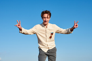 A Caucasian man from Spain making victory signs with both hands on clear sky background