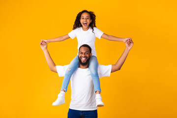 Obraz premium Cheerful African American Man Riding Excited Daughter On His Shoulders