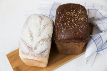 Two breads light and dark yeast-free wholesome on a wooden board lies on a light background, minimalism, close-up