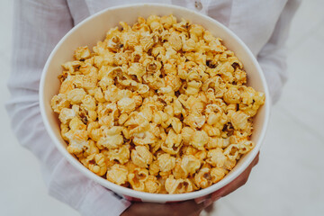 Close-up photo of a young sweet girl, who is holding a tube of popcorn in her hands.