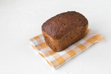 Whole grain bread with seeds dietary lies on a half chick on a light background, fresh hot baked goods, minimalism