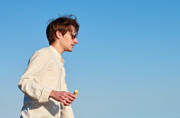 A Caucasian man with glasses from Spain holding a ripe yellow banana on clear sky background