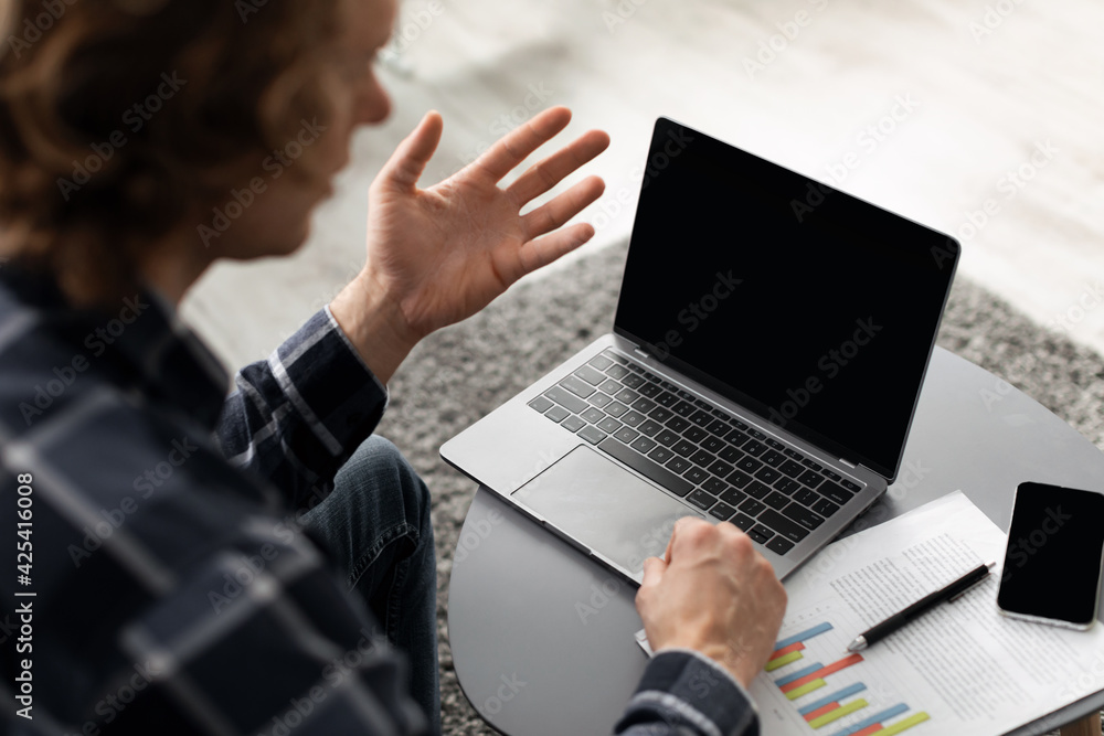 Poster guy making video call on laptop with empty screen indoor