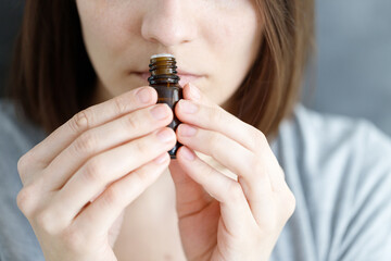 young and beautiful Caucasian women sniff a tube of aromatic oil, to check for covid-19 symptoms or a female perfumer sniffs a new perfume fragrance for women