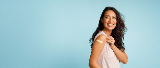 Woman Showing Vaccinated Arm With Bandage After Injection, Blue Background - obrazy, fototapety, plakaty