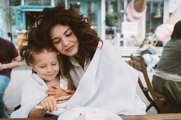 Young mom eating cake with smiling kid on the street