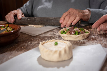 Older woman and young woman making traditional Mallorcan empanadas. Mallorcan empanadas. Easter traditions. Hands doing culinary activities.