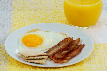 Fototapeta premium Fried fresh egg and bacon on white plate and orange juice 