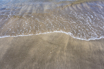 Waves and beach sand with empty space for text. Perfect for traveling or summer vacation content. 