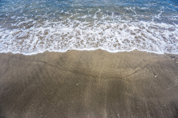 Waves and beach sand with empty space for text. Perfect for traveling or summer vacation content. 