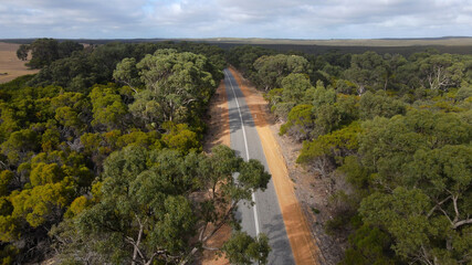Fototapeta na wymiar Aerial view along empty beautiful rural road during sunny day surrounded by forest trees