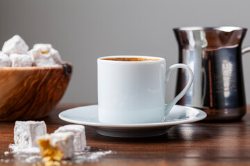 Traditional Turkish coffee served in classical cups with Turkish delights. A metal coffee pot is in the background.