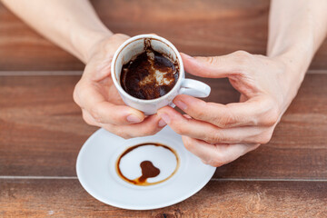 A caucasian woman is performing fortune reading ( kahve fali ) using leftover coffe grounds in ceramic Turkish coffe cup. A popular activity in Turkey. Coffee drops form shapes and patterns.