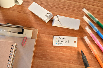 There is a a word card with Chief Financial Officer written on it. They are on the desk along with...