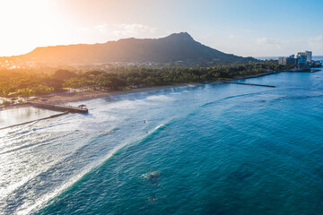 Diamond Head Mountain and Waikiki Queens Beach during sunrise. Palms on the beach with light...