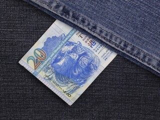 Hong Kong banknote of twenty dollars between blue denim fabric