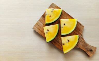 Slice of yellow watermelon on cutting board