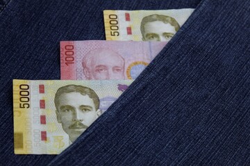 stacked Costa Rican banknotes between blue denim fabric