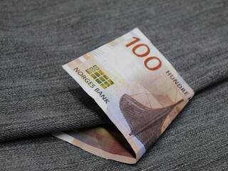 norwegian banknote of 100 kroner between blue denim fabric