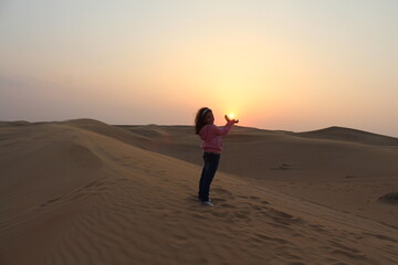 Fototapeta na wymiar Little girl looking at the Sunset at Dubai's Desert by Christian Gintner