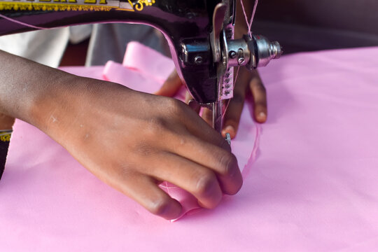 African tailor fashion designer hands sewing a pink cloth with a sewing machine in a tailor shop 