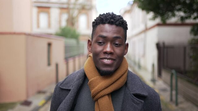 Confident black man walking in city during winter season, person walks forward looking at camera