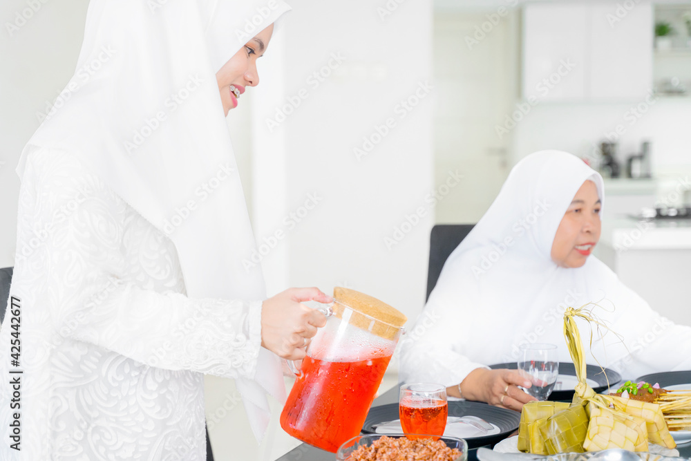 Wall mural muslim woman pouring drink while having dinner