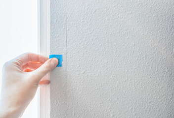Person hand stick blue sticker on paint cracked wall, checking quality house from defect...