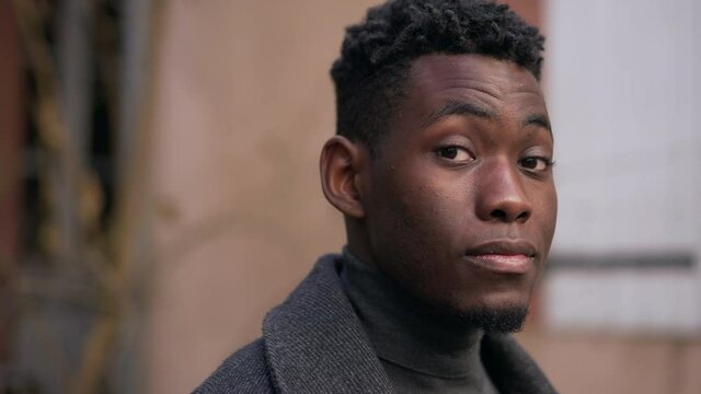 Confident young black man standing outside staring camera portrait face close-up