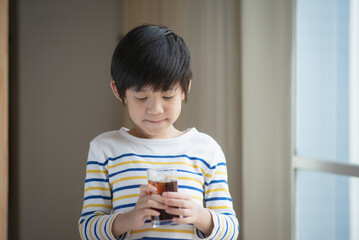 Little asian boy drinking soft drink coca cola soda
