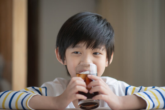 Little asian boy drinking soft drink coca cola soda