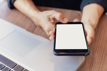 Top view female hands holding smart phone with blank white screen. Women hands workspace, close-up hand holding smartphone blank screen for text and content on wood table background.