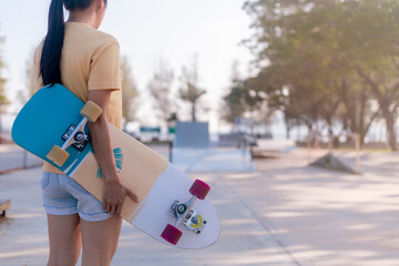 Close up on young women hand hold skateboard, surf skate on public skate ramp park background. Free relax skateboard surf skate trendy concept. Fashion portrait of female hands holding surf skateboard © SSTC STUDIO