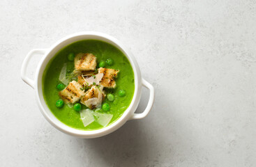 Broccoli and green peas soup-puree in white bowl close up