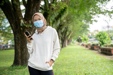 pretty muslim woman athlete with face mask looking at camera while outdoor exercise
