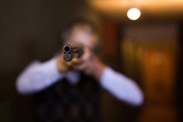 Man aims at a target with a double-barreled gun in a shooting range