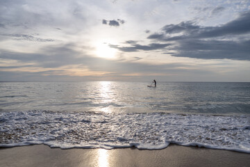Sunset on the sea with silhouette of man with a Paddle on a SUP board