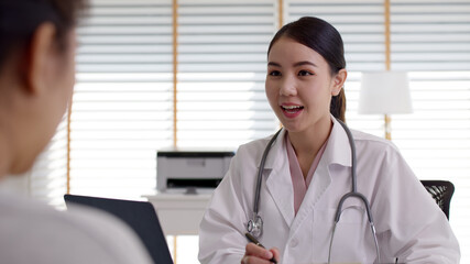 Attractive beautiful young asia doctor female wear white gown stethoscope on shoulders diagnosis talk to sick patient provide help counseling consult, therapy or explain prescribe in office clinic.