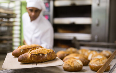 Baker pulls hot bread out of the oven