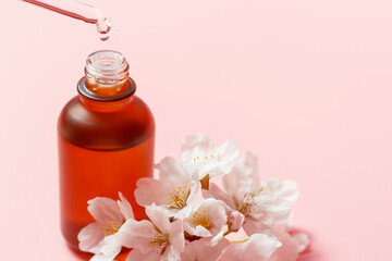 Bottle with serum and pipette on pink background close-up, copy space.