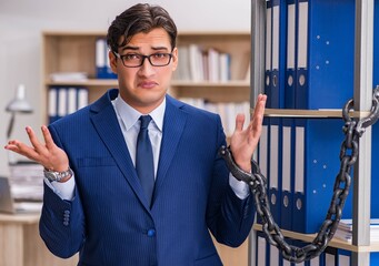 Young man standing next to the shelf with folders