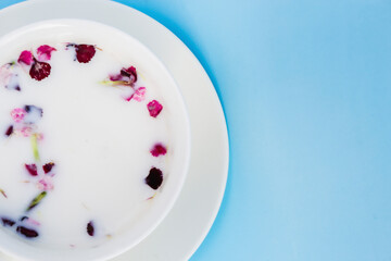 White Cup with vegan milk and flowers on a blue background. Concept of vegetarian drinks and food, herbal teas, beauty and health, Spa