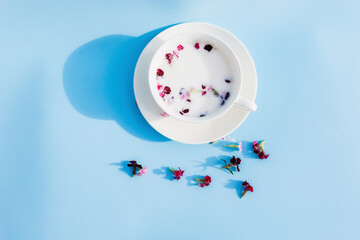 White Cup with vegan milk and flowers on a blue background. Concept of vegetarian drinks and food, herbal teas, beauty and health, Spa