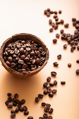 black arabica coffee beans, aromatic in a coconut dish, sprinkled beans on the table, light background, close-up, top view