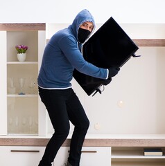 Man burglar stealing tv set from house