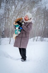 Portrait of an elderly woman with a dog. Woman with pekingese dog walking on the snowy field.