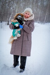 Portrait of an elderly woman with a dog. Woman with pekingese dog walking on the snowy field.