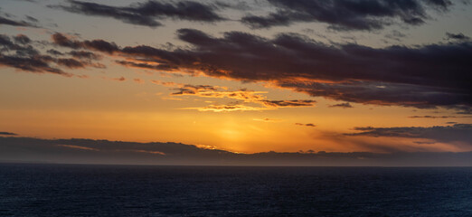 An evening cloudscape panorama with vivid colors in the sky and dark clouds.