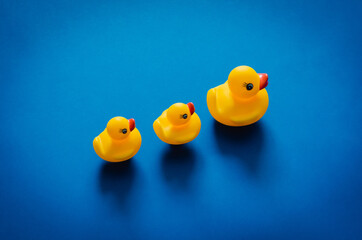 Yellow rubber duck mother leading her babies on blue background. Minimal mother day concept.